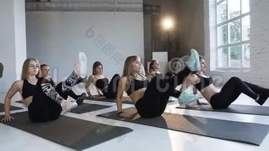 一群年轻运动员和教练一起在健身课上在地板上表演健身健美操。 瑜伽的概念