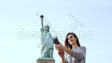 美丽快乐的白种人旅游妇女在<strong>纽约</strong>市<strong>自由女神像</strong>与智能手机拍摄自拍照片。