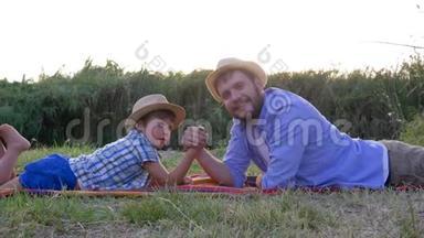 在乡村夕阳的映衬下，幸福的父子俩在户外躺在格子花格子上，一起玩摔跤