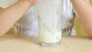一个孩子通过吸管从杯子里喝<strong>牛奶</strong>，把气泡吹成玻璃杯。 一杯<strong>牛奶特写</strong>..