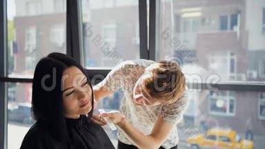 在理发师`，一位满脸笑容的黑发女人在一家理发店里，在一位男理发师面前给她理发