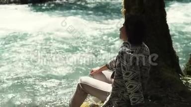 在公园散步的女人坐在河边看着水