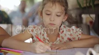 一个小女孩用彩色铅笔画画。 坐在屋里