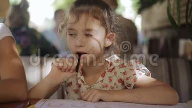小女孩正在咖啡馆里画画。 一个小女孩用彩色铅笔画画。 坐在屋里