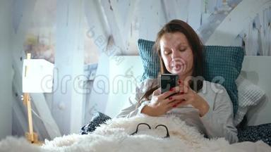 戴眼镜的女人躺在床上，睡前使用智能手机