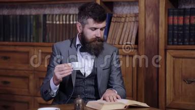 一个可敬的人在图书馆里喝早茶看书。一个留着胡子的聪明人看书。