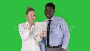 年轻的高加索女商人和她的非洲同事用平板电脑在绿色屏幕上打视频电话，ChromaKey。