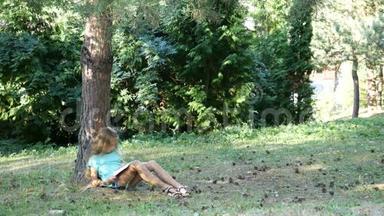 一个十几岁的女孩在<strong>树下看书</strong>。 公园里的夏日阅读