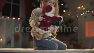 可爱的女孩在发光的圣诞树下玩玩具熊，节日前夜