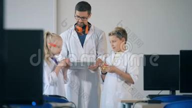 孩子们和一位导师站在实验室的房间里，看着新印刷的塑料模型。