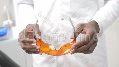 戴上医用橙色安全眼镜。 年轻的非裔美国男医生，戴着医用面具的牙医。 医学、卫生