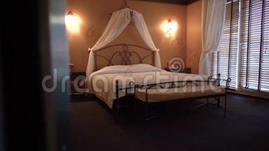 漂亮的双人床坐落在一个舒适的小酒店房间里。摄像机从左向右移动。