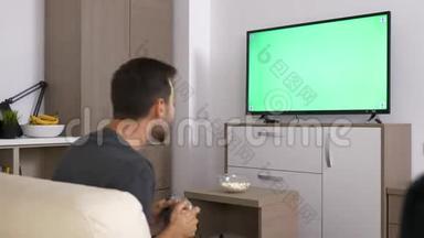 一名男子在大等离子电视绿色模拟屏幕前的控制台上玩电子游戏