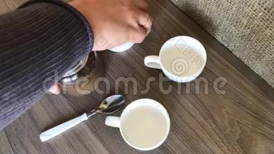 一个人把开水速溶咖啡倒在白色的咖啡杯里。