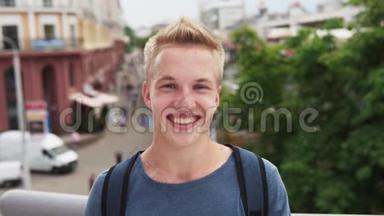 年轻快乐的男学生微笑着看着城市大街的镜头