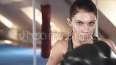 专注运动的黑发女人对着镜头拳击。做刺拳，拳击，钩拳和上勾拳。