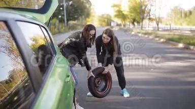 两个女人从车里拿出备用车轮在地上滚动