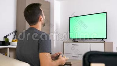 成人男子在绿色大屏幕电视前在控制台上玩电子游戏