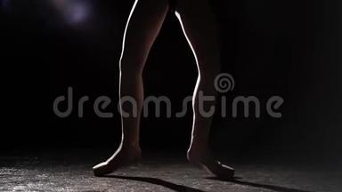 慢镜头芭蕾舞演员在聚光灯下的黑色背景在演播室。 芭蕾舞演员表演经典芭蕾舞表演