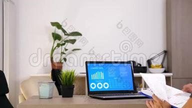 男人在电脑屏幕上看动画公司的数据，同时检查一些文件