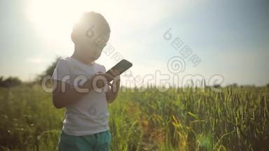 小男孩站在田野的中央，使用智能手机，玩<strong>游戏</strong>，<strong>发布</strong>照片。 有趣，现代的孩子