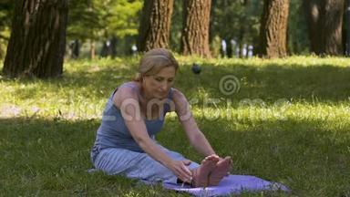 年轻的女士在公园的<strong>垫子</strong>上伸展，瑜伽，业余的，好的形状缓慢的运动