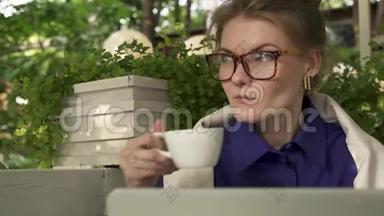 戴眼镜的嬉皮士女孩在她笔记本电脑附近的<strong>夏日咖啡</strong>馆喝<strong>咖啡</strong>