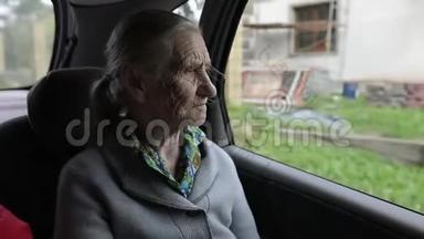 一个满脸皱纹的悲伤老妇人望着车窗外。