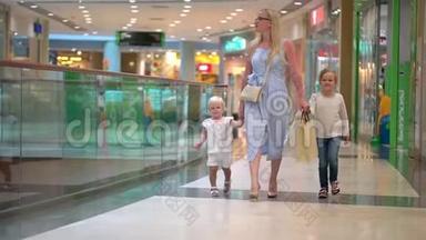 现代家庭的购物日。 孩子们在购物中心和母亲在一起。 快乐的一家人在购物。 在商场里的家人。