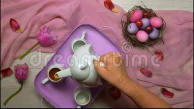 双手放在桌子上，放一个托盘，上面放着带鸡蛋的复活节巢背景上的茶