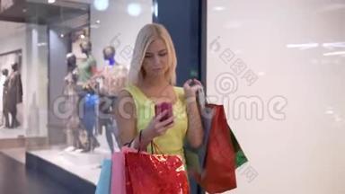 时尚购物，迷人的女孩在逛商场的季节使用智能手机在网上商店购物