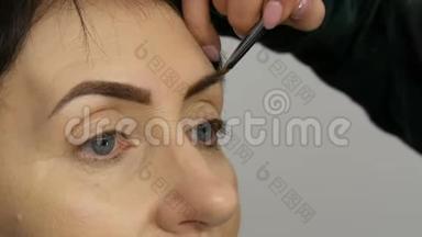 一种特殊的画笔用眉毛阴影描绘眉毛。 近景。 专业化妆师化妆到中间