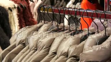 在商场`购物中心的服装店里，各种各样的女式冬季夹克衫挂在衣架上