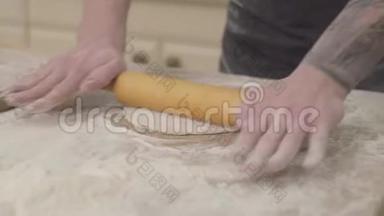 在厨房里，用面团<strong>擀</strong>面杖在家里用围裙把年轻的披萨制造商的<strong>手</strong>收起来准备面团。 概念