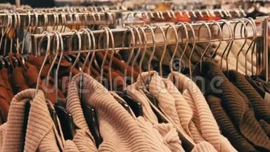 一大批妇女`温暖的衣服挂在衣架上，躺在购物中心的服装店的货架上