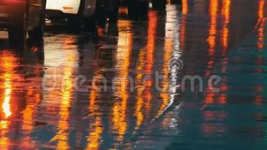 汽车在交通，前灯在雨中的沥青，视图下面。 晚上雨打水坑。 汽车`灯光的反射