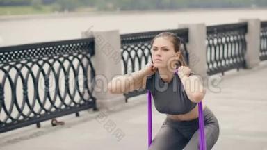健身妇女使用运动<strong>扩张</strong>器蹲在户外健身训练