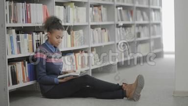 年轻的非裔美国妇女正<strong>坐在</strong>学校图书馆的<strong>地板上</strong>看书。