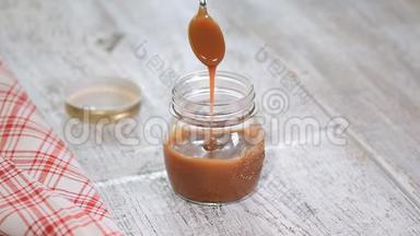 自制咸焦糖酱在罐子里的乡村木桌背景。