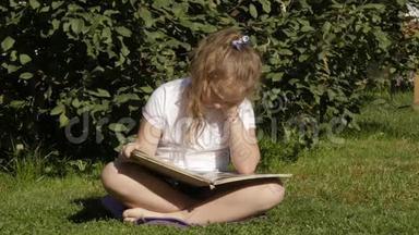 美丽的少女坐在夏天公园的草地上看书。 慢动作
