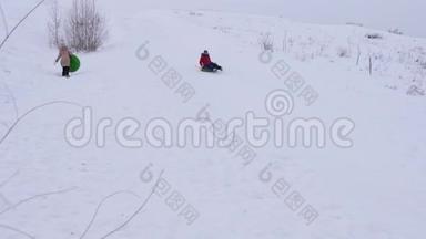 快乐的女孩从大雪中滑出一个充气的雪管。 孩子们在圣诞节假期在公园里玩冬天的游戏