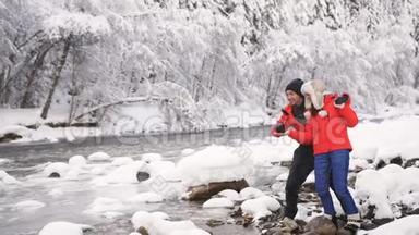一对相爱的夫妇在冬天的森林里向流过<strong>美丽风景</strong>的溪流扔石头。