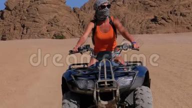 一个骑四方自行车的女孩在埃及沙漠山脉的背景下骑着自行车。 慢动作