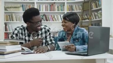 微笑非洲男女学生使用平板电脑在图书馆。