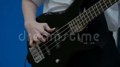 男青少年<strong>低音</strong>吉他手演奏黑色电吉他。 特写镜头。 一个少年的手指在用<strong>低音</strong>吉他拉弦.