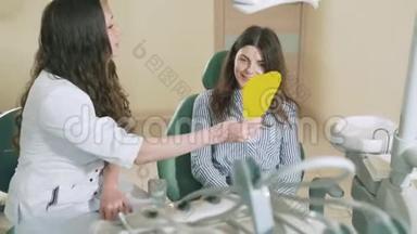 一位女<strong>牙医</strong>告诉她的病人，牙套已经对齐了她的牙齿，显示了x光。 一个看<strong>牙医</strong>`女孩