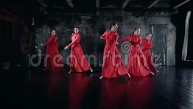 十几岁的女孩在<strong>排练</strong>室里表演舞蹈，穿着红色的裙子，跳跃和旋转