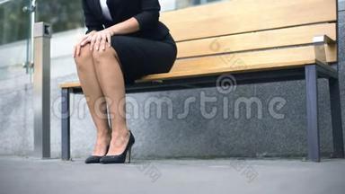 商务小姐坐在长凳上，等着在街上和合伙人见面