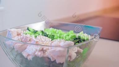 特写，慢动作，沙拉在一个玻璃沙拉碗鸡肉和绿色植物调味香料。 的概念