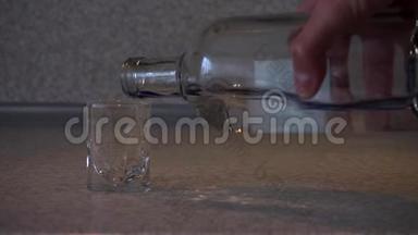 桌子上有一个空酒杯，一只手从透明的瓶子里倒伏特加，取出酒杯